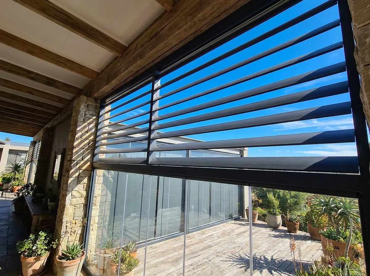 View from a covered Beaulieu stoep looking up at wide external venetian slats against a clear blue sky