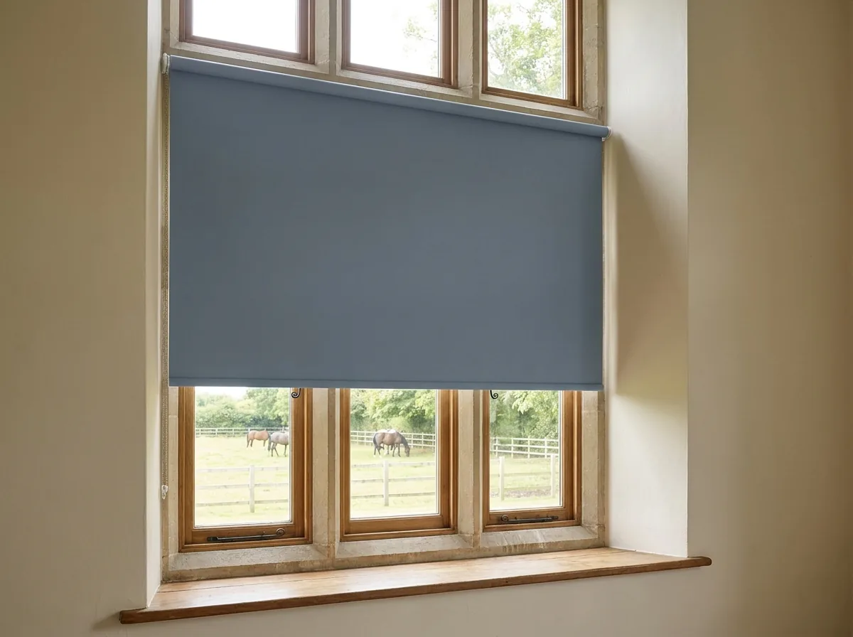 A single flat blockout roller blind, no folds or pleats, part-lowered over a bedroom window in a Beaulieu-style home, paddock still visible below the blind line